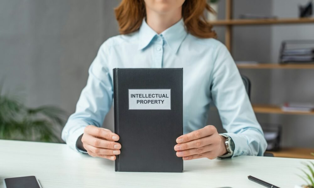 Cropped view of female lawyer showing book with intellectual property lettering, while sitting at