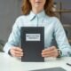 Cropped view of female lawyer showing book with intellectual property lettering, while sitting at